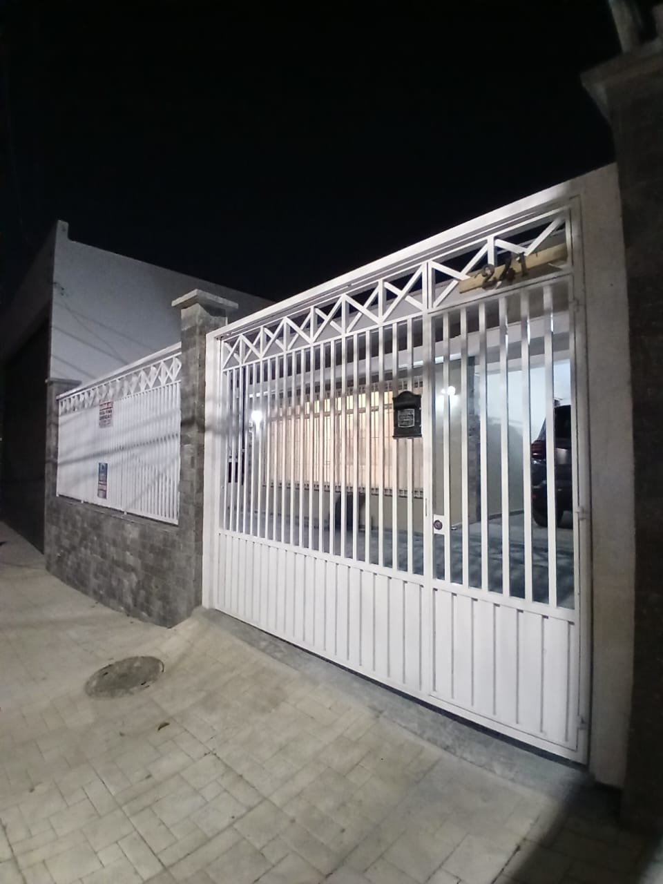 Fachada da casa comercial na Avenida Itamarati, 241, em Santo André, com portão branco gradeado, muro de pedra e o número 241 aplicado no portão.