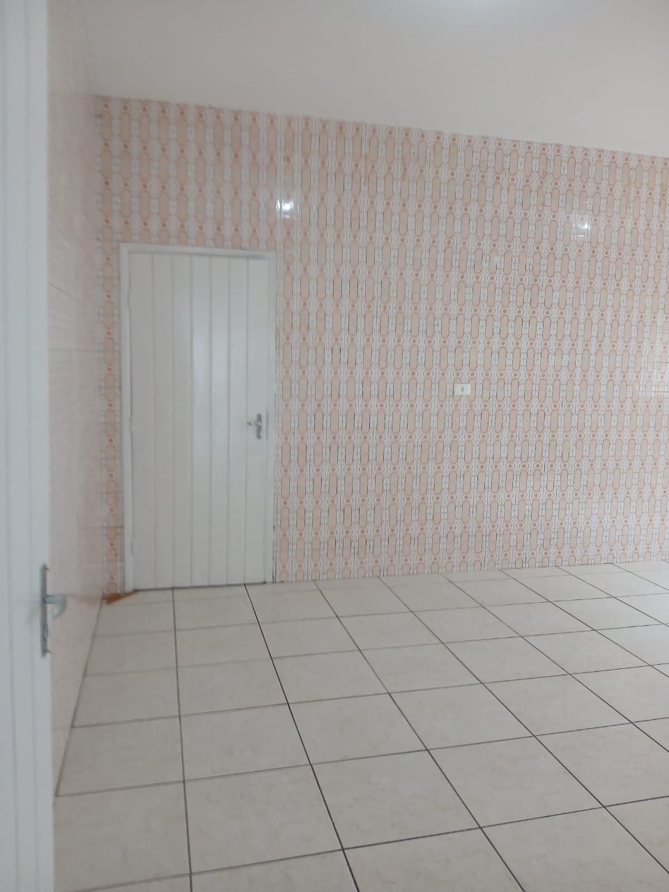 Ambiente menor de apoio, vazio, com azulejo original nas paredes e porta branca.